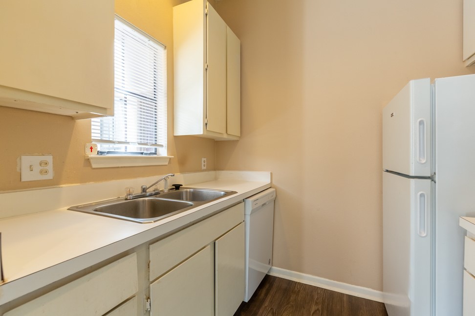712 Graham Place, Unit 305 Austin, TX 78705 - Photo 9 of 18 Kitchen featuring white appliances, dark wood finished floors, light countertops, and white cabinetry