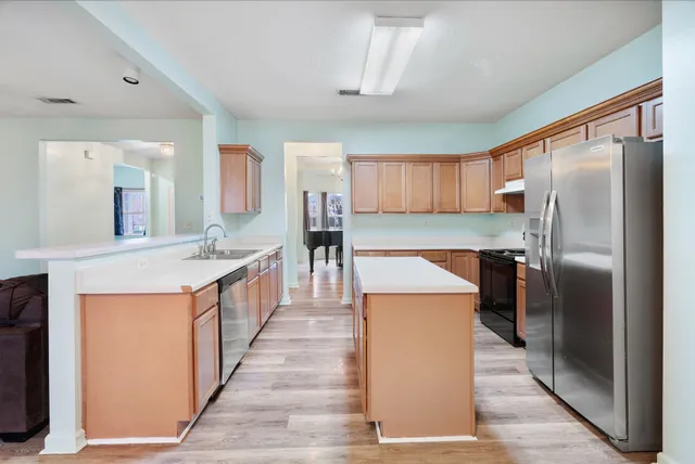 a kitchen with stainless steel appliances granite countertop a refrigerator a stove and a sink