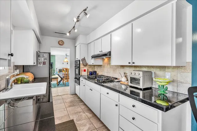 a kitchen with stainless steel appliances a sink stove and cabinets