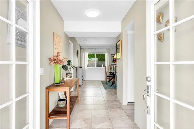 a view of a dining room and livingroom with furniture wooden floor a rug a painting and a chandelier