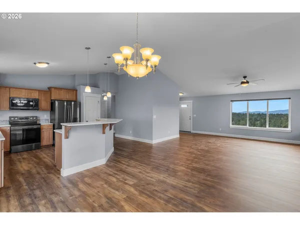a view of a kitchen with kitchen island stainless steel appliances wooden floor and living room view