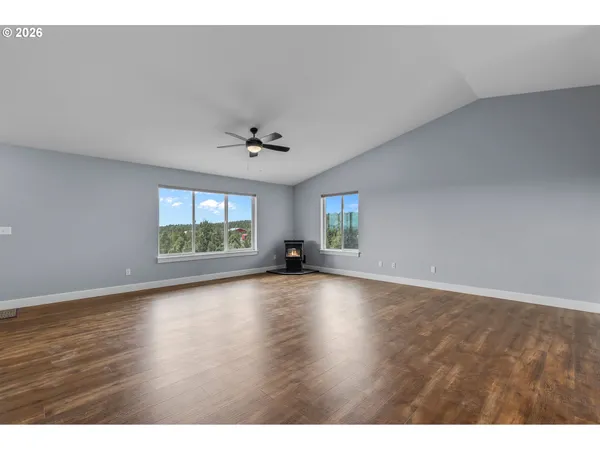 a view of an empty room with a window and wooden floor