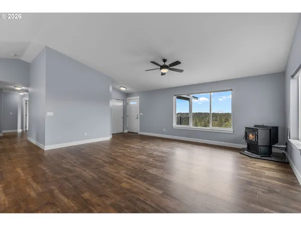 a view of an empty room with a window and wooden floor