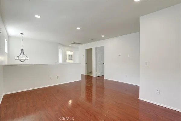 a view of an empty room with wooden floor and windows