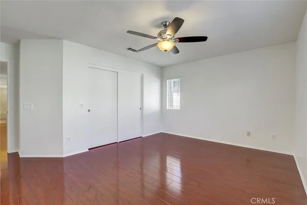 an empty room with wooden floor a ceiling fan and windows