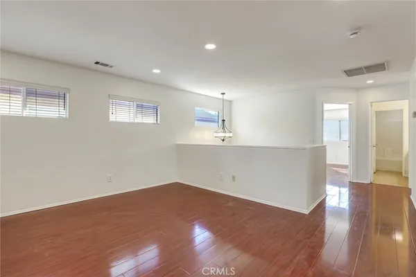 a view of an empty room with window and wooden floor
