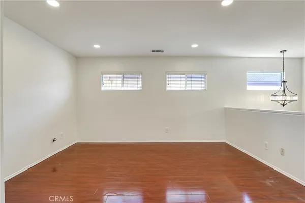an empty room with wooden floor fireplace and windows