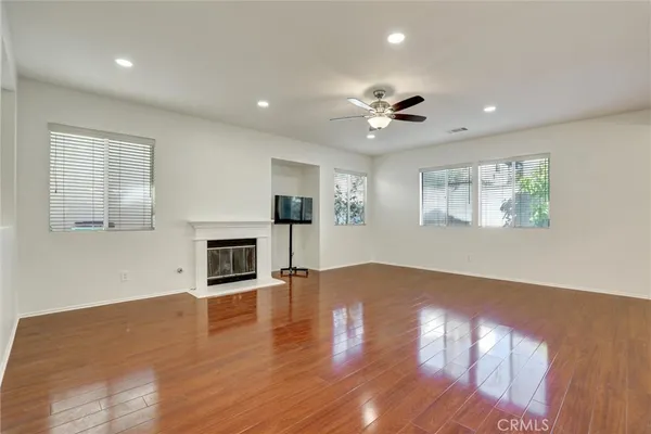 an empty room with windows fireplace and wooden floor