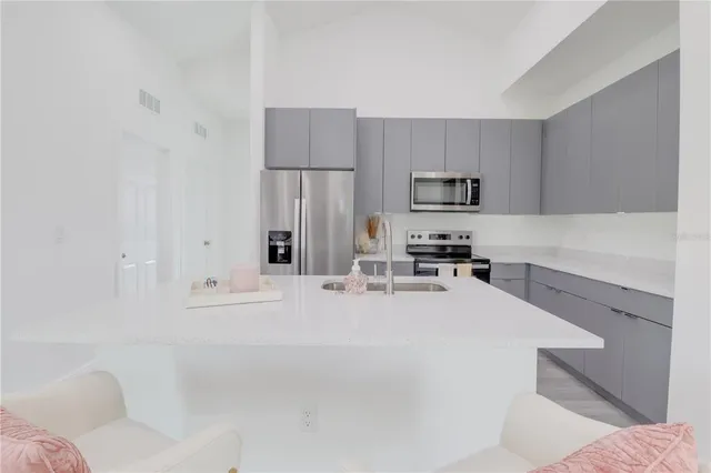 a kitchen with granite countertop a refrigerator sink and white cabinets