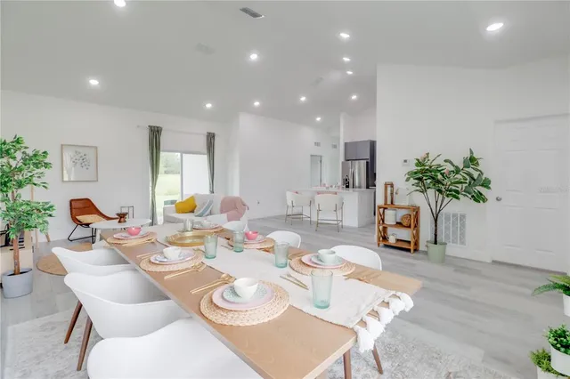 a view of a dining room with furniture a potted plant and wooden floor