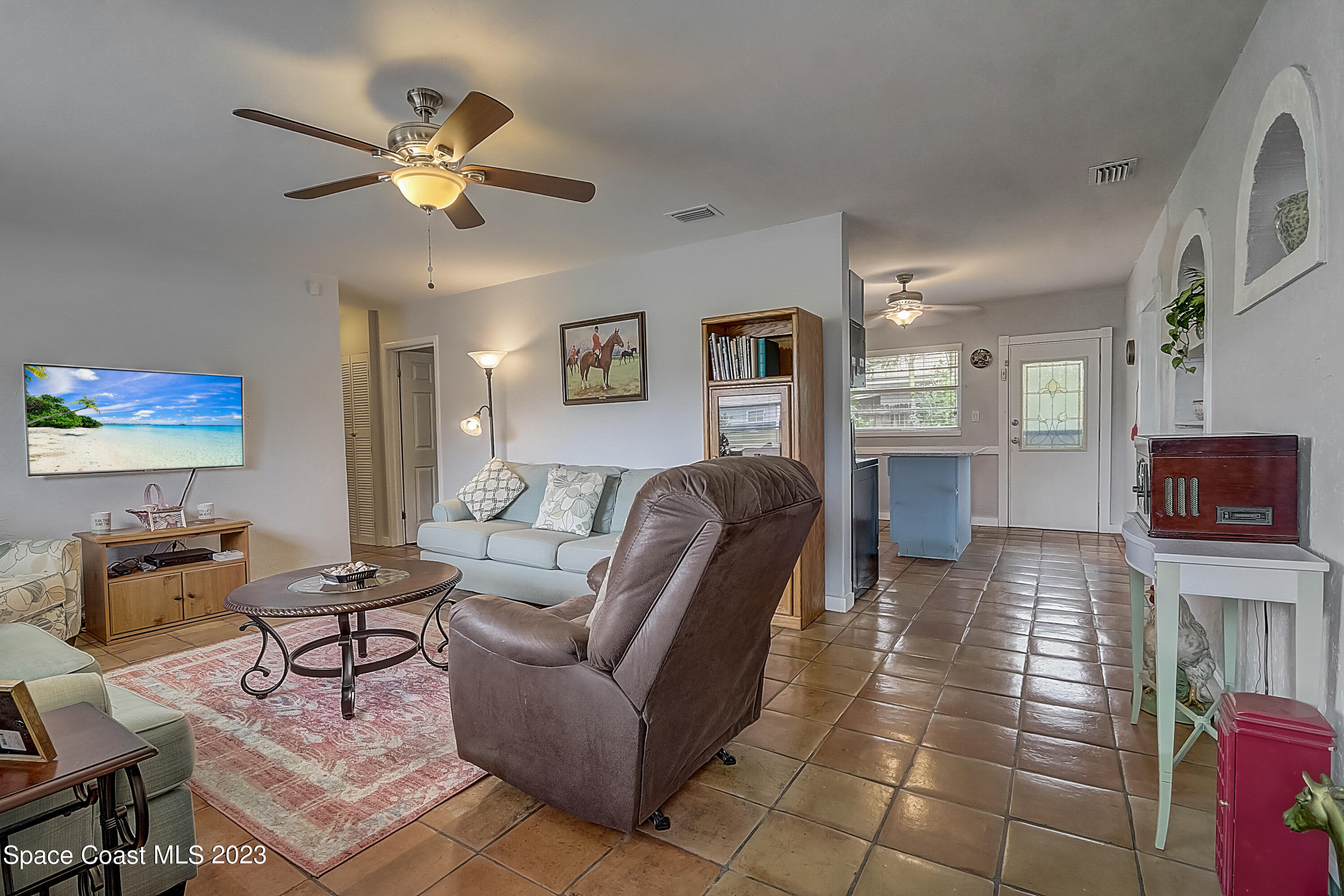 201 Cherry Street Melbourne, FL 32901 - Photo 4 of 22 a living room with furniture a chandelier and a flat screen tv