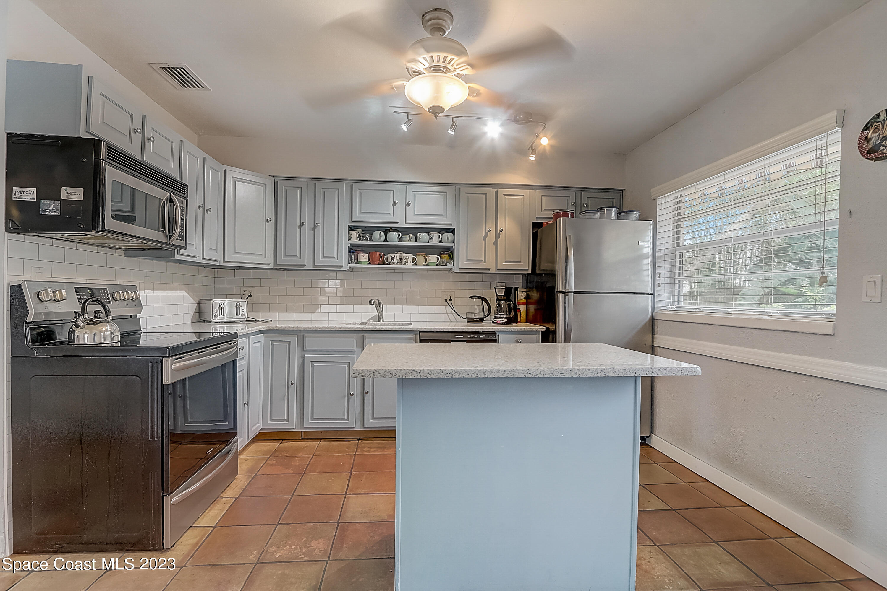 201 Cherry Street Melbourne, FL 32901 - Photo 9 of 22 a kitchen with kitchen island granite countertop a sink appliances cabinets and a counter top space