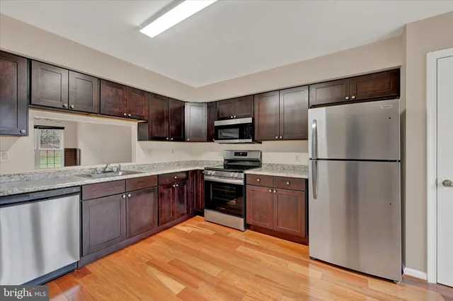 a kitchen with granite countertop stainless steel appliances refrigerator stove microwave and sink