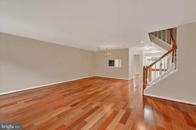 a view of an empty room with wooden floor and stairs