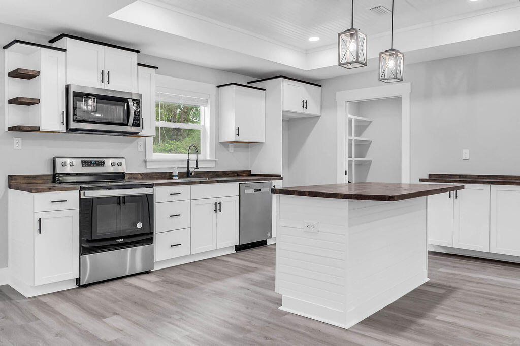 5742 Mt Olive Road Crestview, FL 32539 - Photo 5 of 59 a kitchen with stainless steel appliances white cabinets a sink a stove a microwave and wooden floors