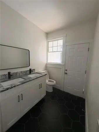 a bathroom with a granite countertop sink a toilet and a mirror