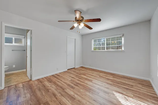 a view of empty room with wooden floor and ceiling fan