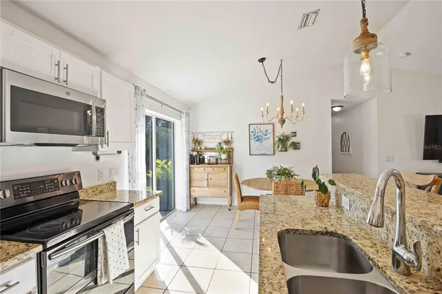 a kitchen with granite countertop a stove a sink and a microwave