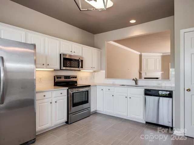 a kitchen with granite countertop white cabinets and stainless steel appliances