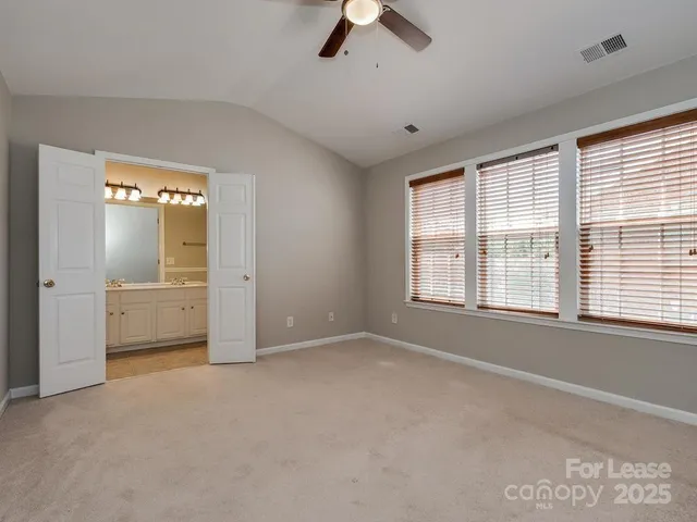 a view of an empty room with a window and a kitchen