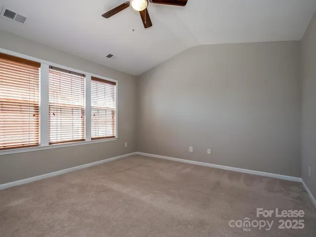 an empty room with ceiling fan and windows
