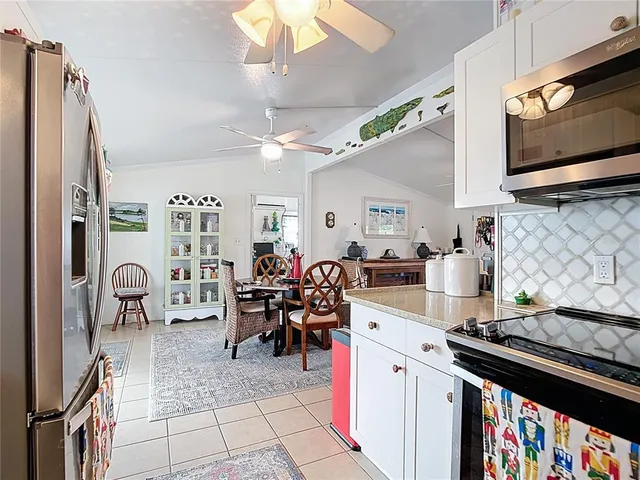 a kitchen with stainless steel appliances kitchen island granite countertop a stove a sink a dining table and chairs with the front door