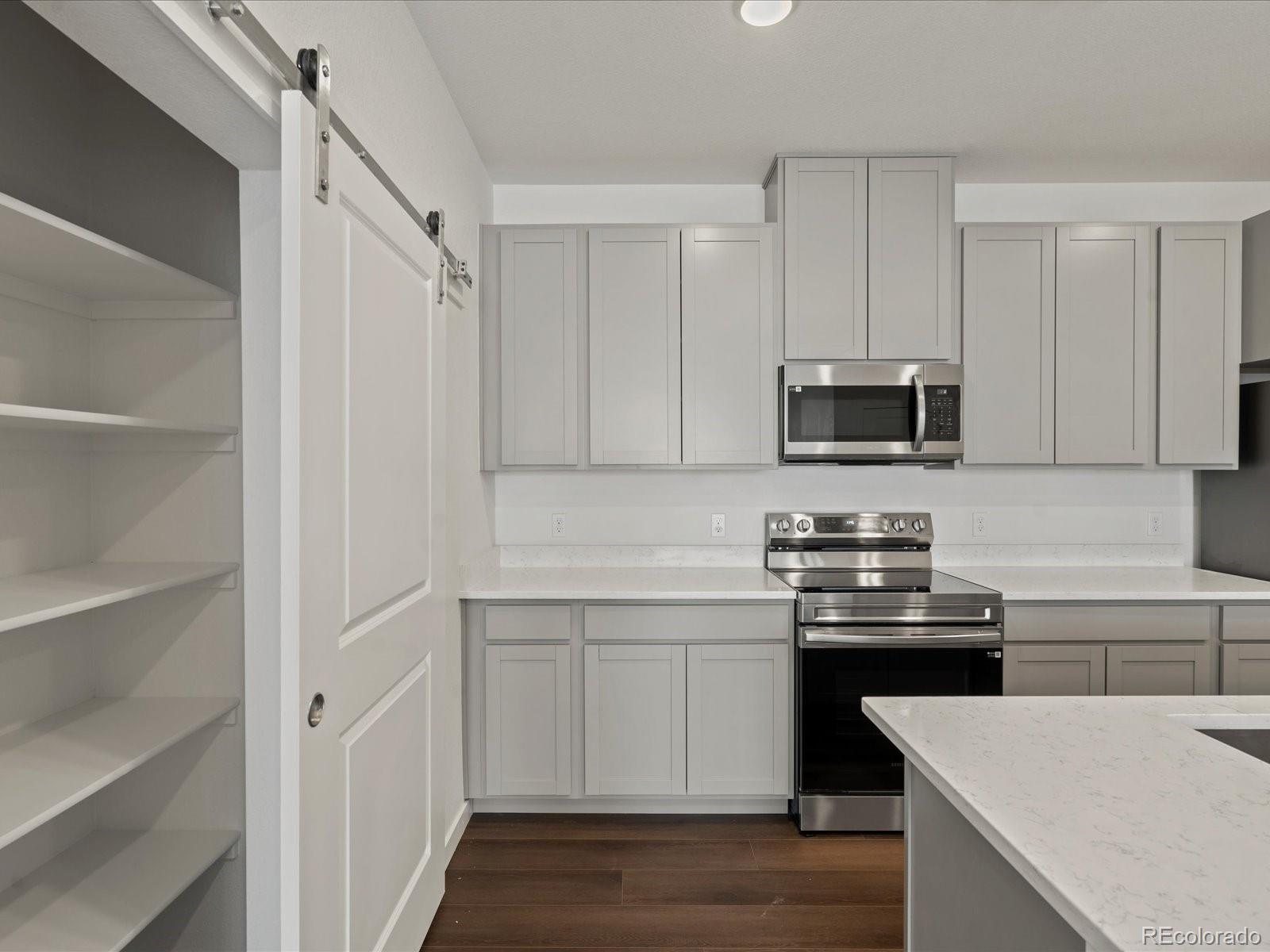 6153 North Ceylon Street, Unit 304 Denver, CO 80249 - Photo 5 of 24 a kitchen with stainless steel appliances a sink a stove a microwave and cabinets