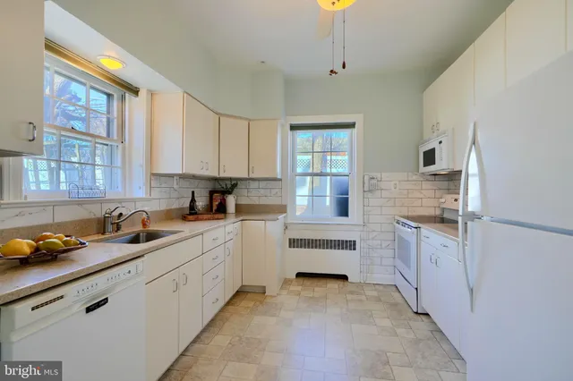 an empty room with wooden floor chandelier fan and windows