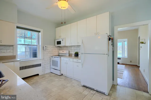 an empty room with wooden floor chandelier fan and windows