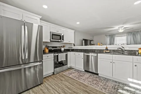 a kitchen with granite countertop a refrigerator stove and sink
