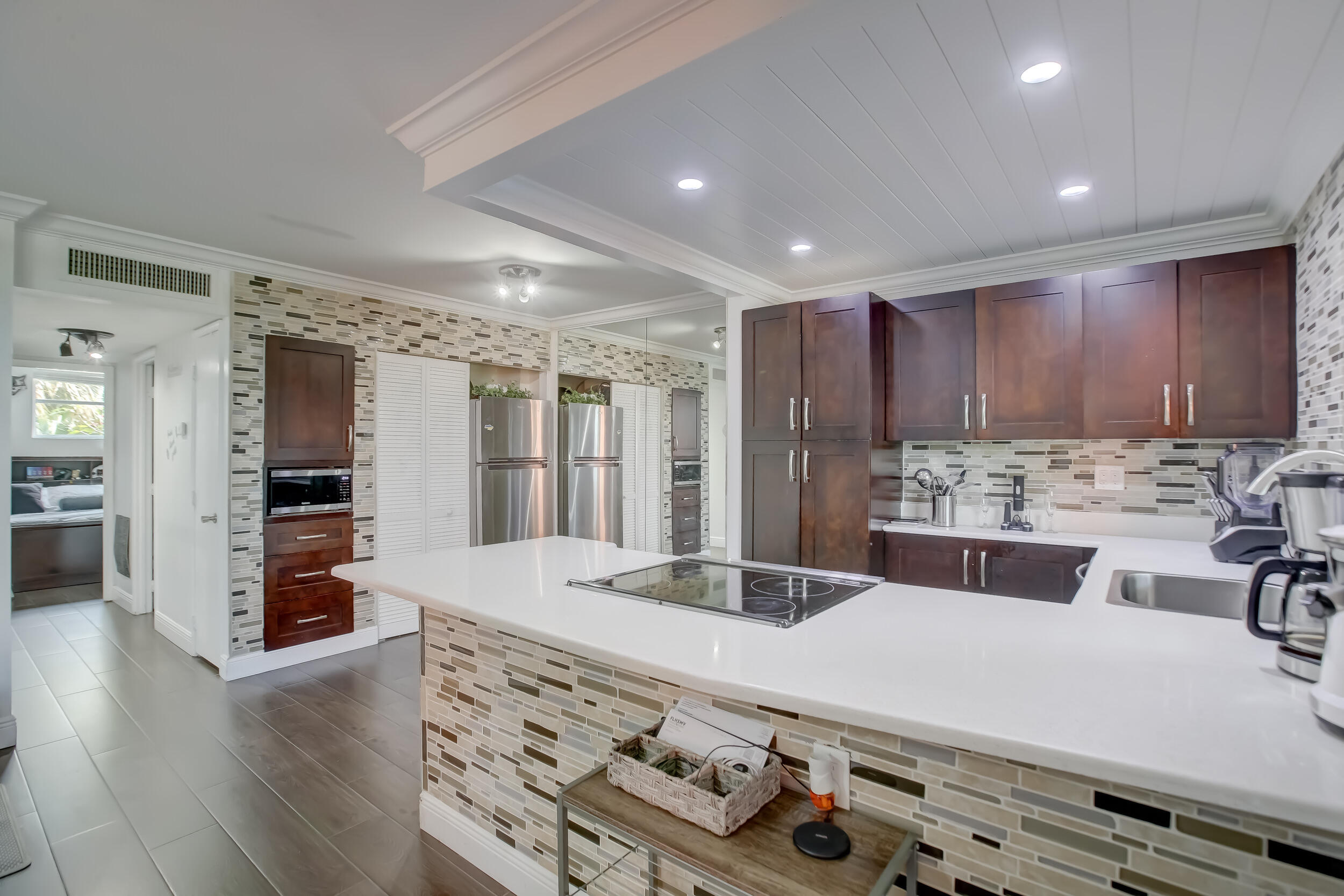 a large kitchen with kitchen island a stove a sink a refrigerator and white cabinets with wooden floor