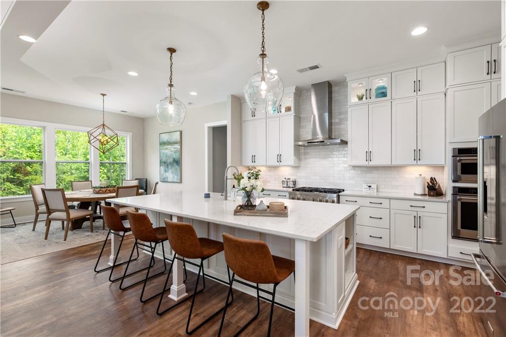 513 Small Batch Path Fort Mill, SC 29708 - Photo 11 of 48 a kitchen with stainless steel appliances granite countertop a stove a sink a refrigerator a dining table and chairs with wooden floor