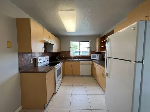 a kitchen with a refrigerator a sink a stove top oven and cabinets