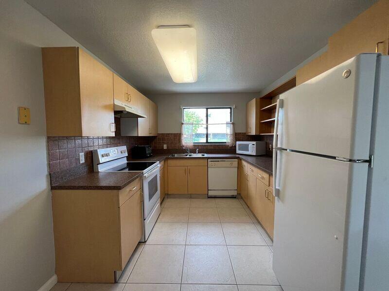 10225 Northwest 33rd Street Sunrise, FL 33351 - Photo 15 of 51 a kitchen with a refrigerator a sink a stove top oven and cabinets