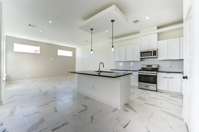 a kitchen with stainless steel appliances granite countertop a stove a sink and a refrigerator