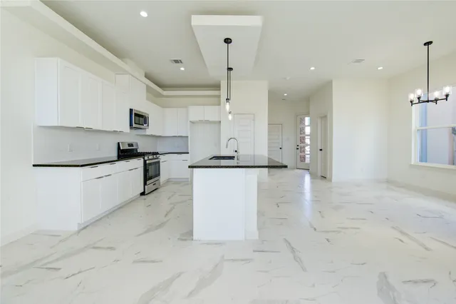 a large kitchen with kitchen island a stove a sink dishwasher and a refrigerator with wooden floor