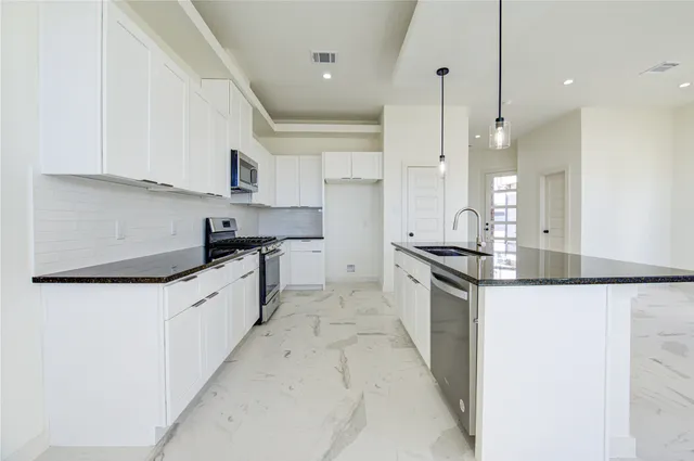 a large kitchen with granite countertop a sink a stove and a refrigerator