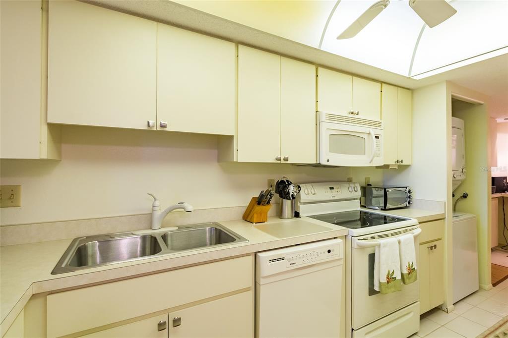 8767 Midnight Pass Road, Unit 506F Sarasota, FL 34242 - Photo 13 of 37 a kitchen with white cabinets and white appliances