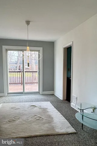 a view of an empty room with window and chandelier fan