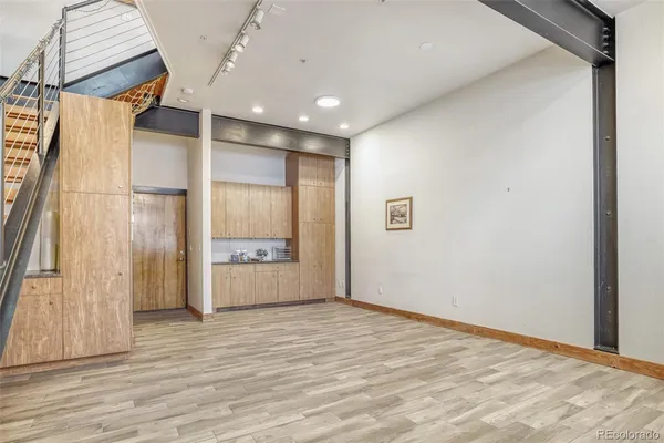 a view of an empty room with wooden floor and stairs