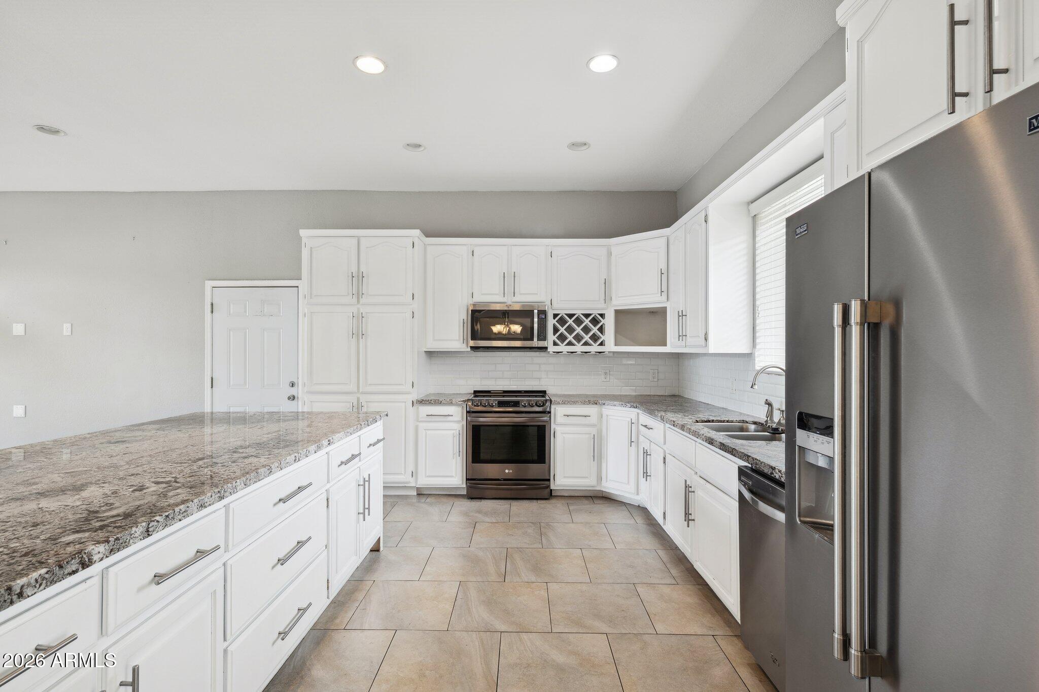 702 West Why Worry Lane Phoenix, AZ 85021 - Photo 11 of 53 a large kitchen with stainless steel appliances granite countertop a stove a sink and a refrigerator