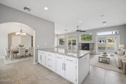 a large kitchen with kitchen island granite countertop a stove a sink a refrigerator and white cabinets