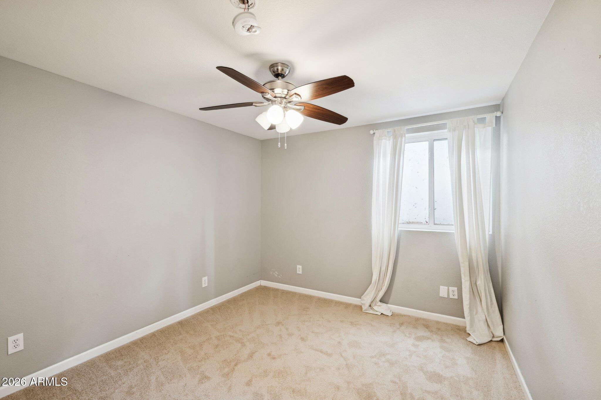 702 West Why Worry Lane Phoenix, AZ 85021 - Photo 25 of 34 an empty room with a window and a fan