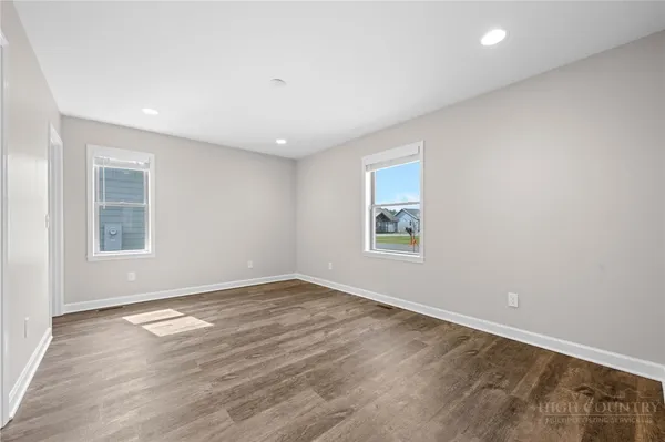 an empty room with wooden floor and windows