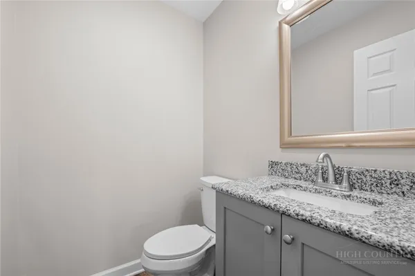 a bathroom with a granite countertop sink a toilet and a mirror