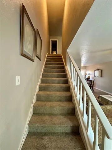 a view of staircase with lots of frames on wall and a window