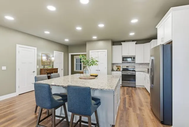 a kitchen with stainless steel appliances granite countertop a refrigerator a stove a sink a dining table and chairs