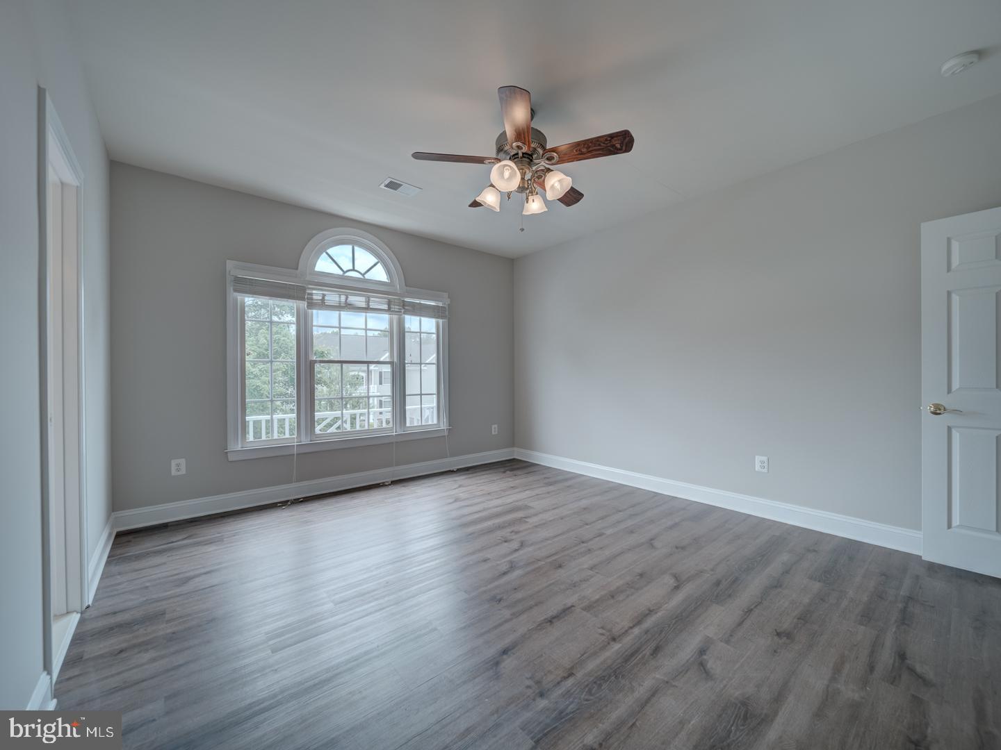 8429 Link Hills Loop Gainesville, VA 20155 - Photo 78 of 102 an empty room with wooden floor chandelier fan and windows