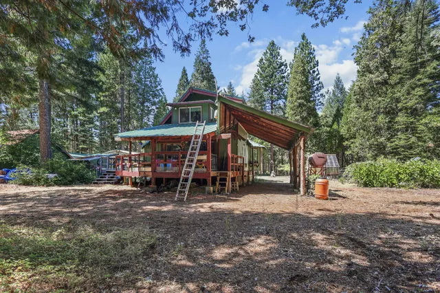 a couple of white house with large trees and wooden fence
