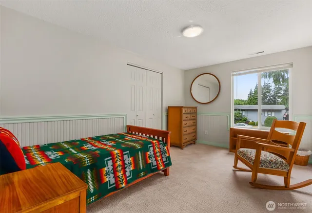 a bedroom with a bed and a dresser next to a window